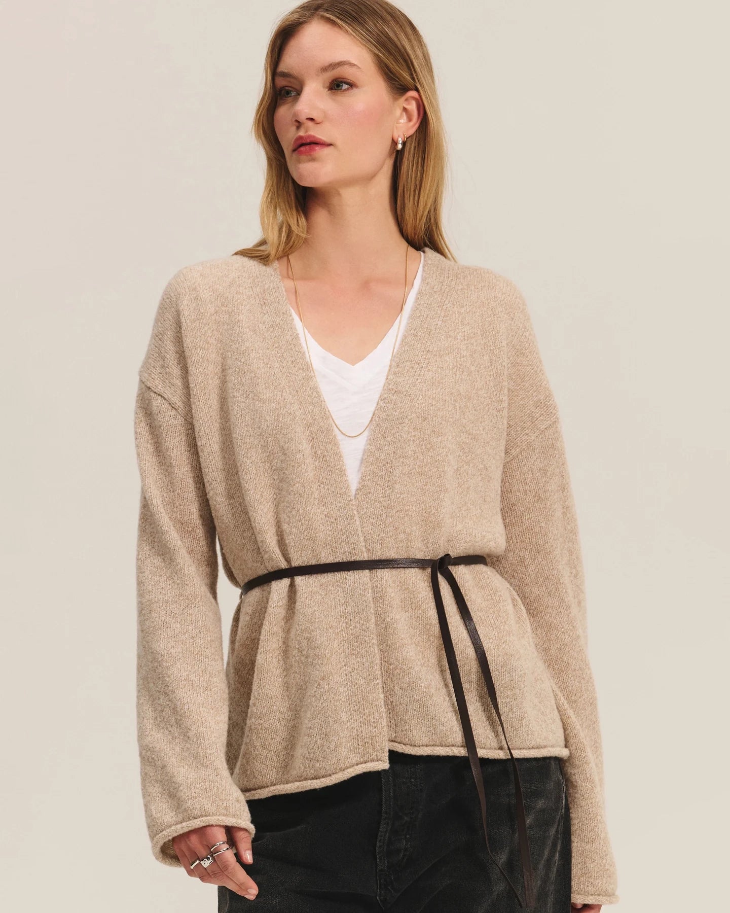 Woman wearing a beige knit cardigan with a thin belt