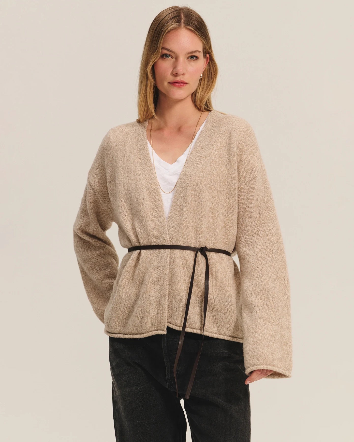 Woman wearing a beige knit cardigan with a thin belt
