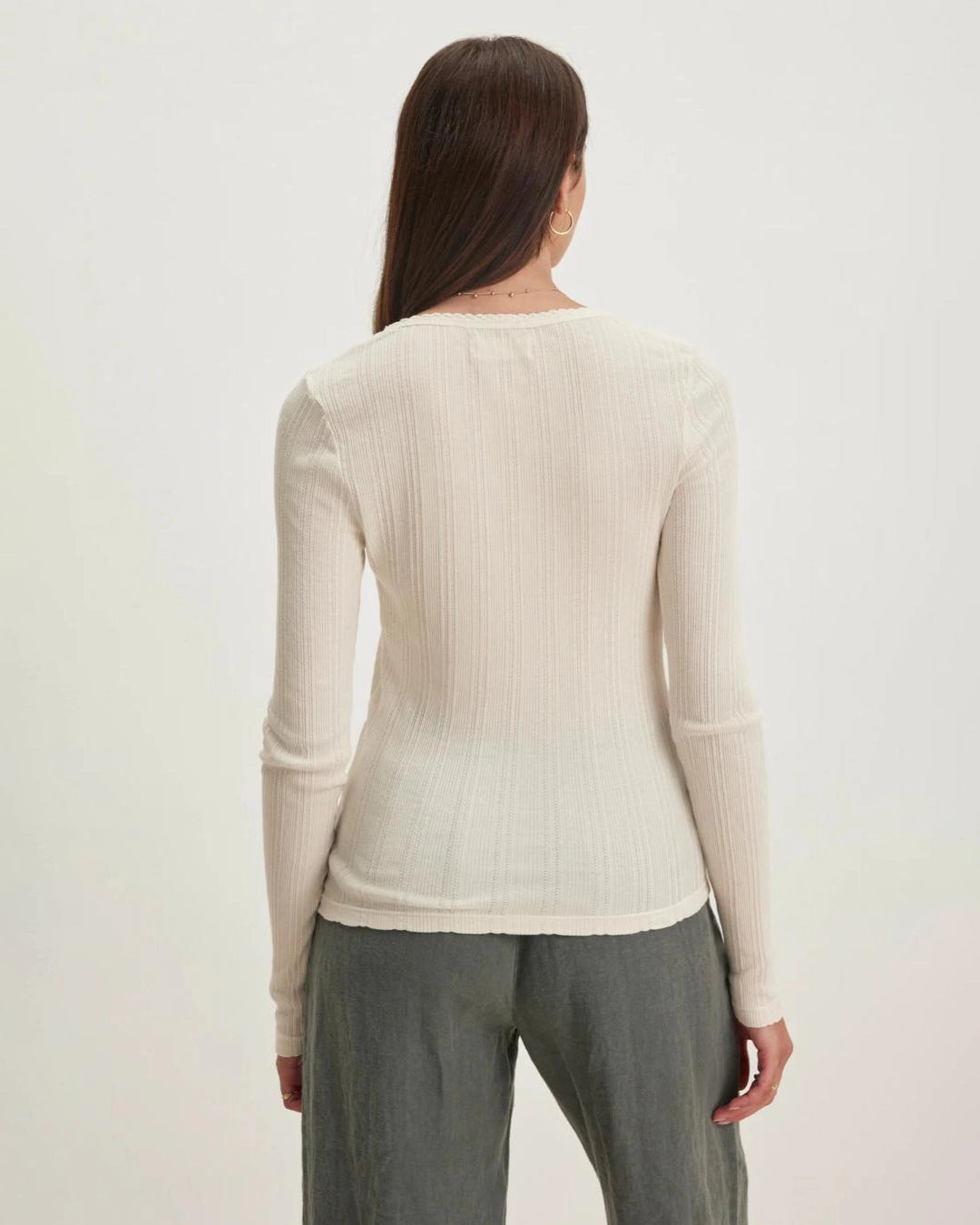 Woman wearing a beige long-sleeve pointelle top