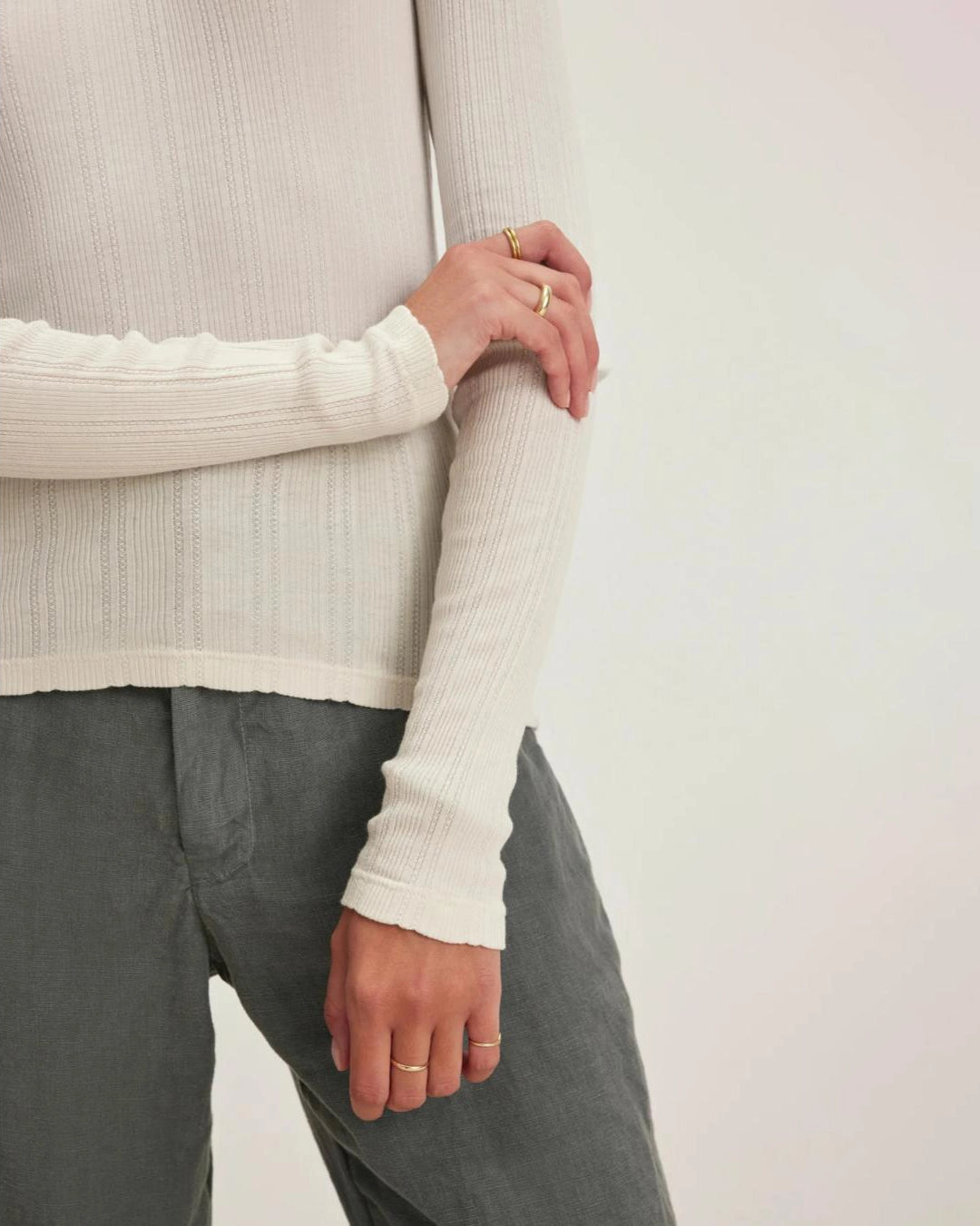 Woman wearing a beige long-sleeve pointelle top