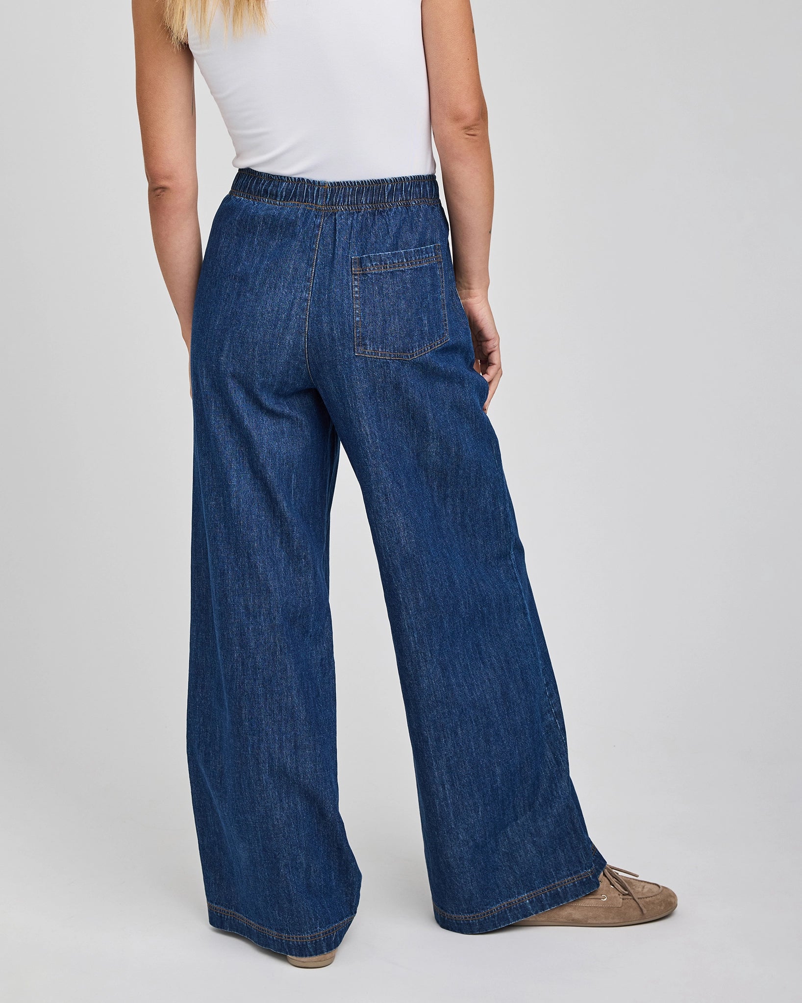 a woman wears a pair of wide leg denim jeans with elastic waist