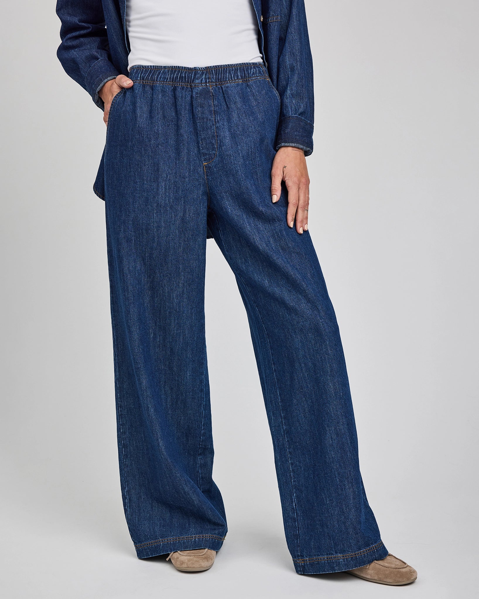 a woman wears a pair of wide leg denim jeans with elastic waist