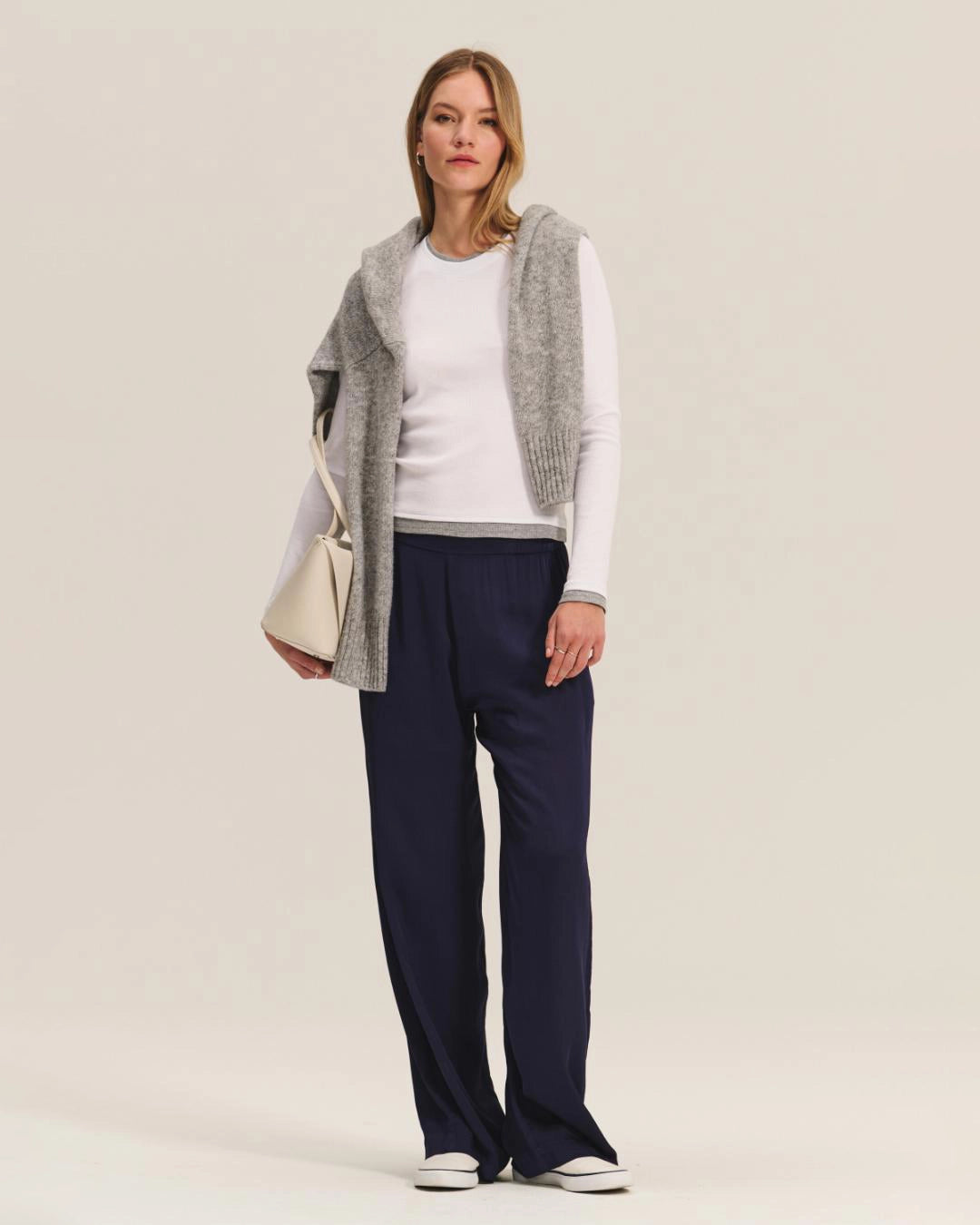 Woman wearing a white long-sleeve top and navy pants