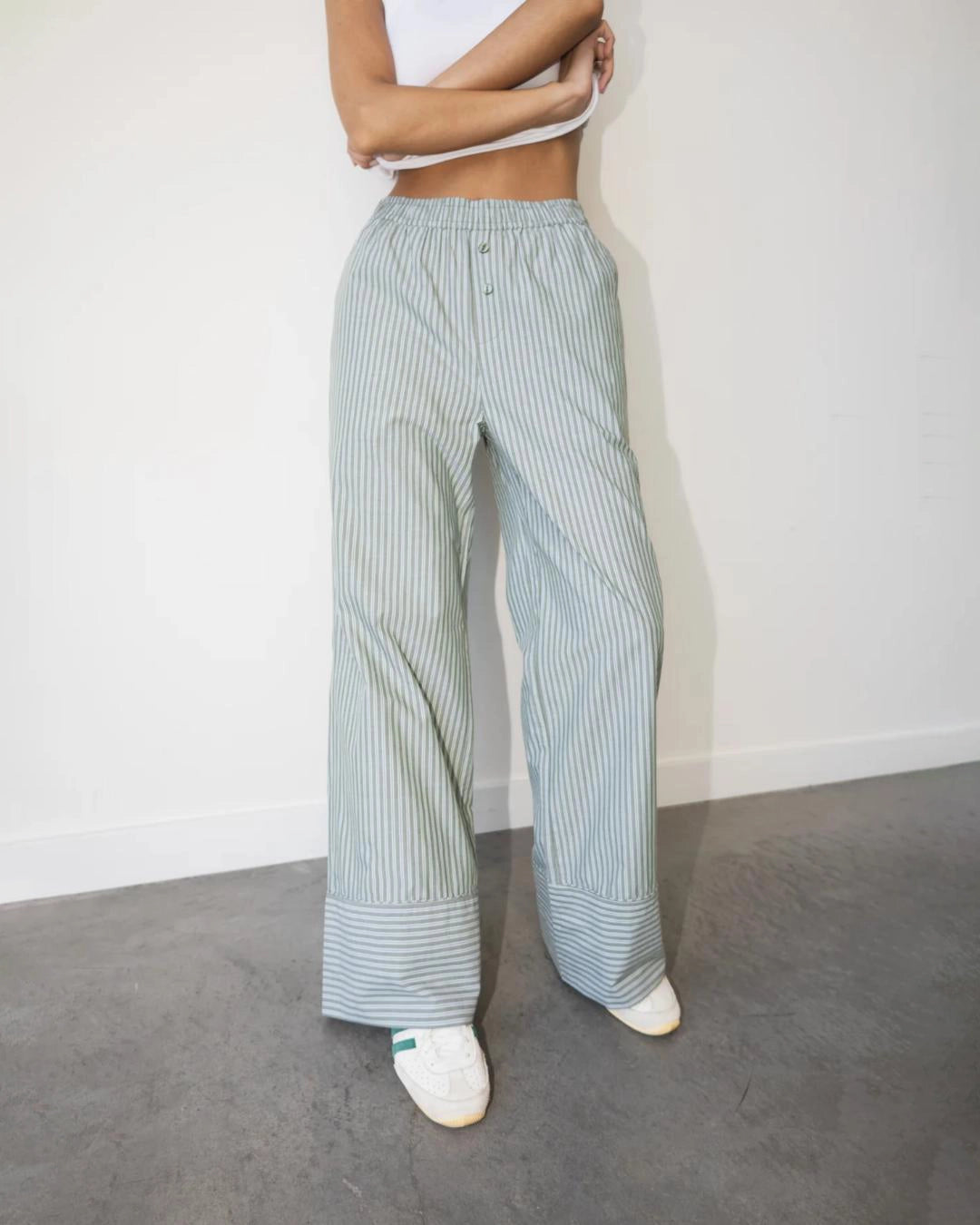 a woman wearing light green striped cotton pants with an elastic waist and buttons with wide hem cuff