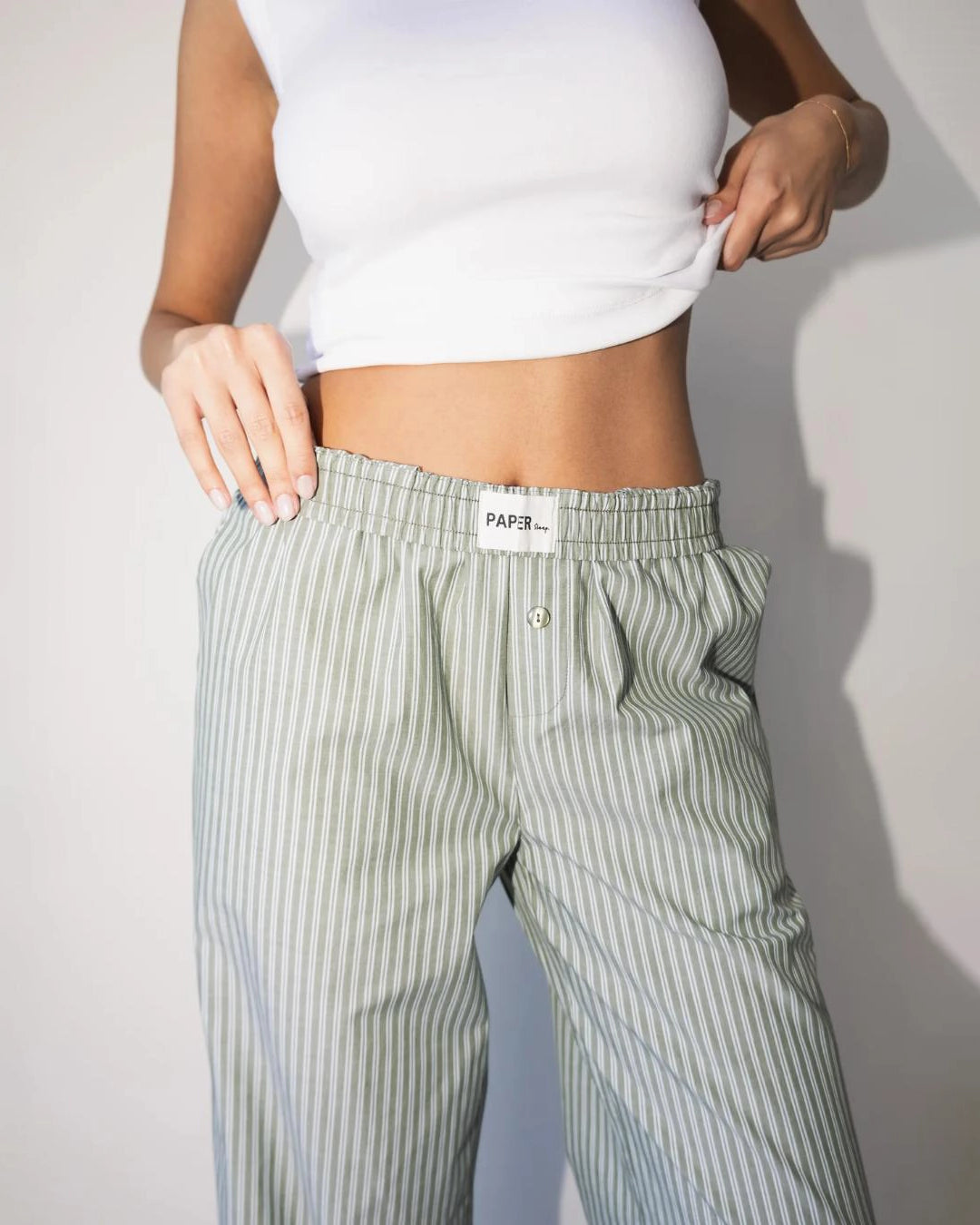 a woman wearing light green striped cotton pants with an elastic waist and buttons with wide hem cuff