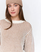Woman wearing a striped knit beige and white sweater