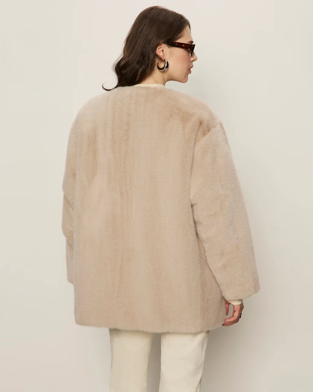 Woman wearing a beige faux fur coat with gold buttons
