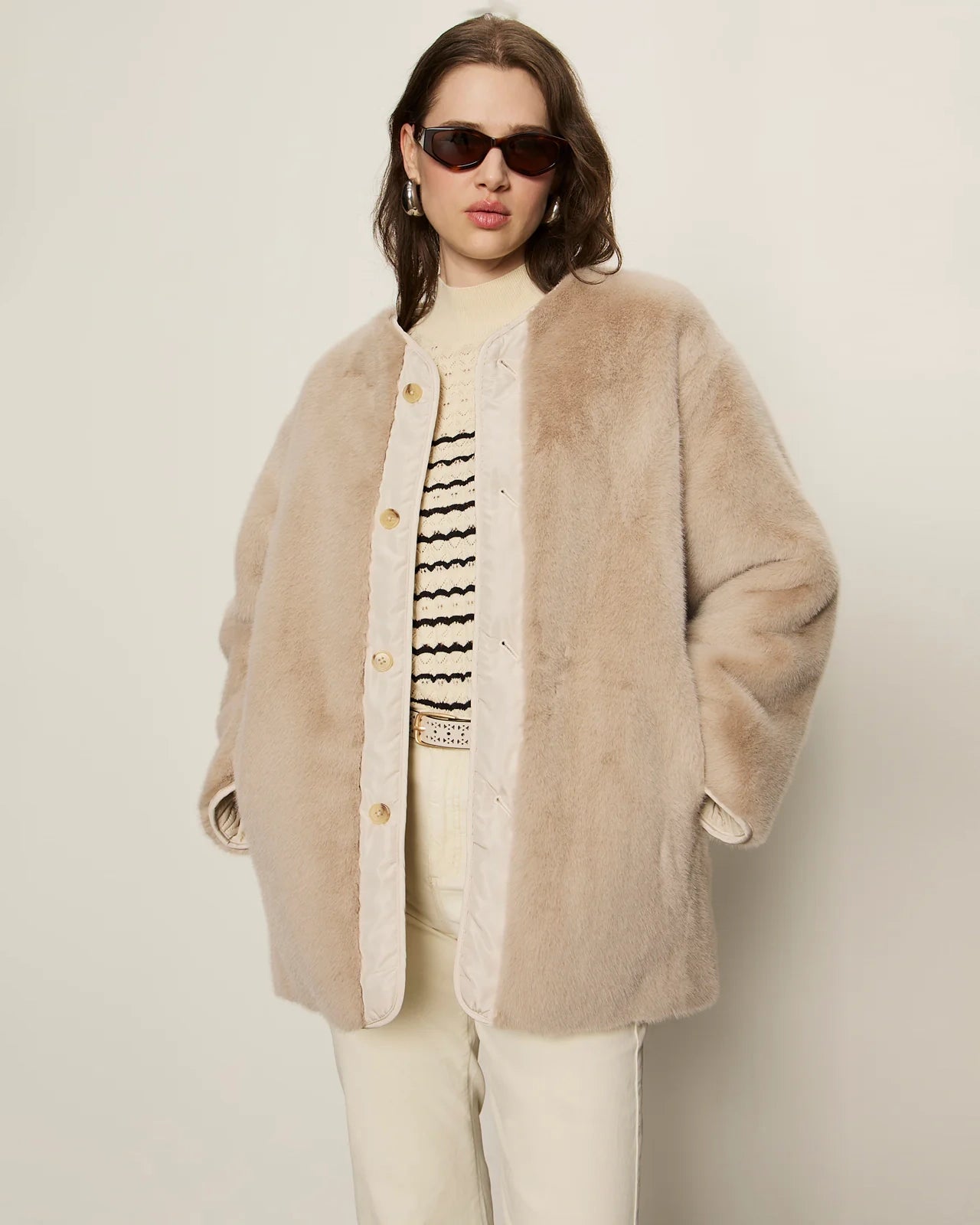 Woman wearing a beige faux fur coat with gold buttons
