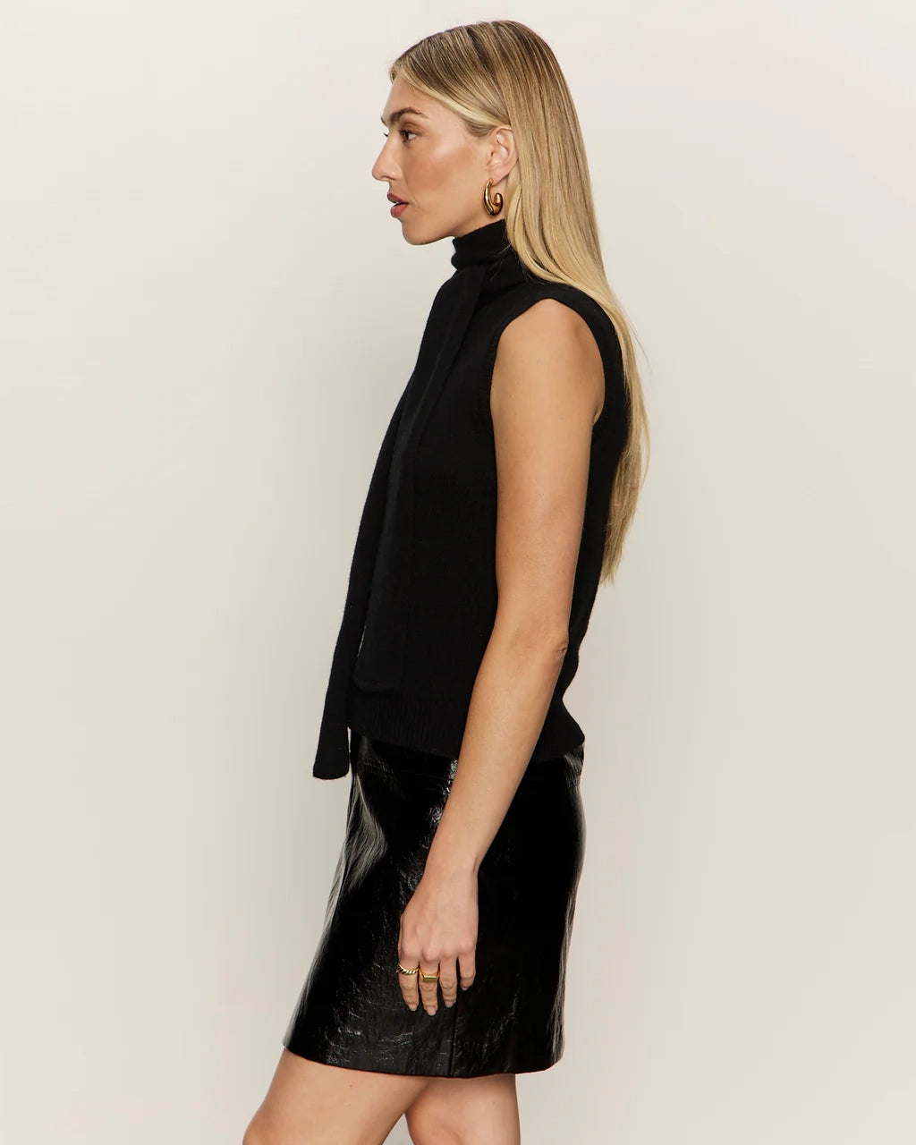 Woman wearing a black sleeveless sweater with scarf detail