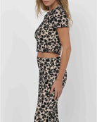 a woman wears a cropped t-shirt in beige with black flowers all over by sage the label