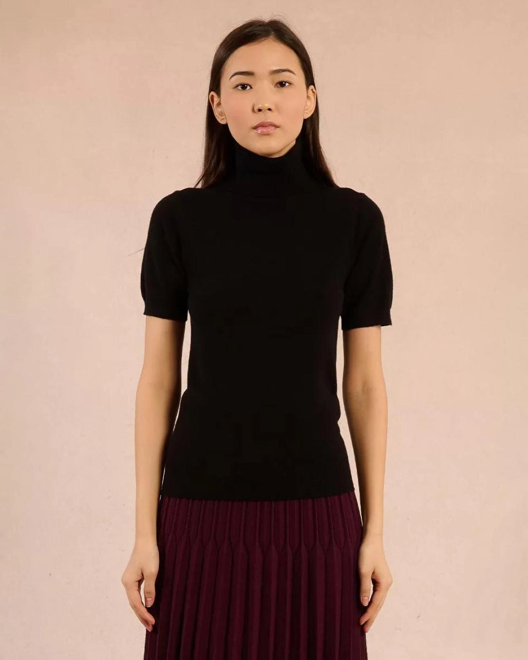 Woman wearing a black turtleneck tee sweater and maroon skirt