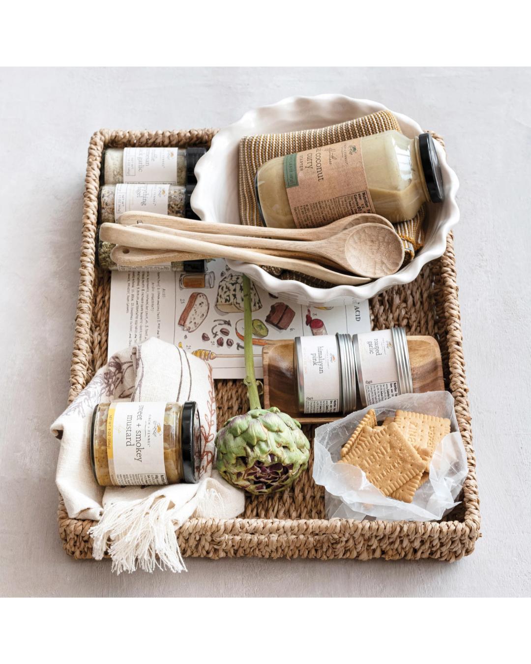 Basket with various items including a bottle, a spoon, and a piece of artichoke on a light background