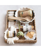 Basket with various items including a bottle, a spoon, and a piece of artichoke on a light background