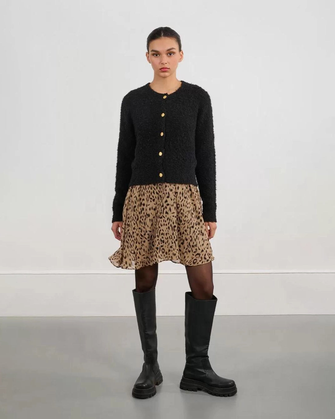 Woman wearing a black fluffy cardigan with gold buttons