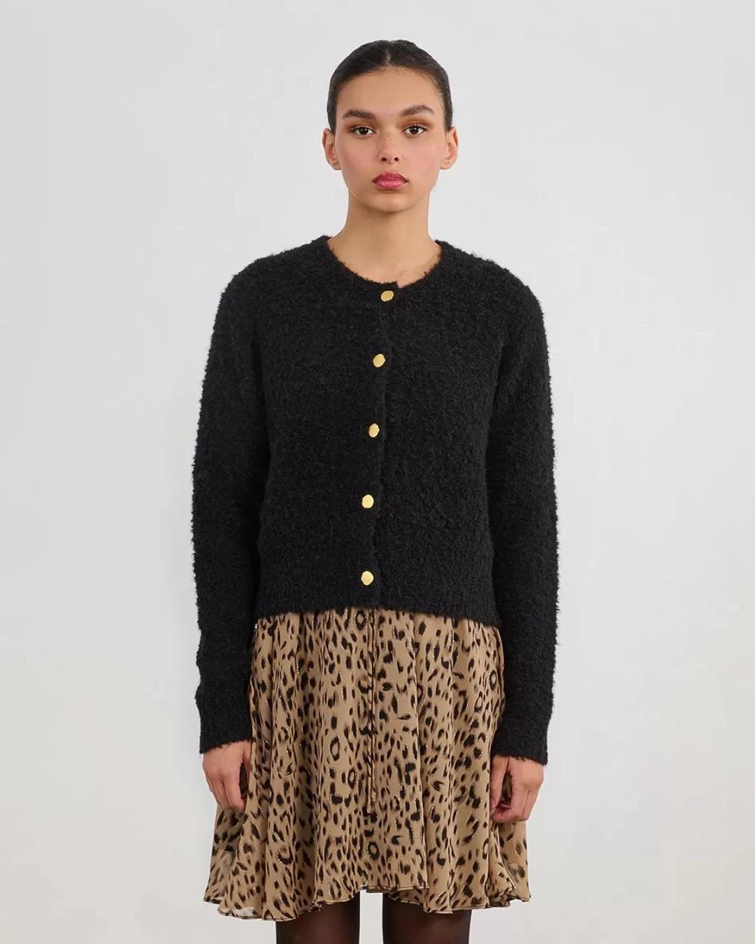 Woman wearing a black fluffy cardigan with gold buttons