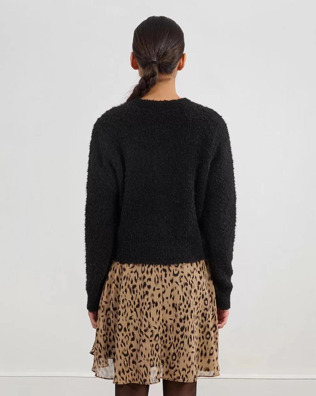 Woman wearing a black fluffy cardigan with gold buttons
