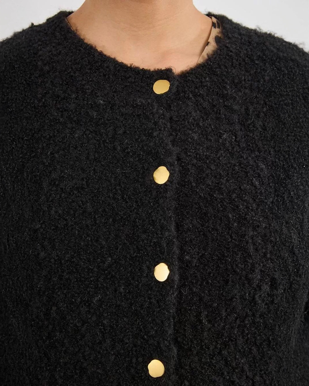 Woman wearing a black fluffy cardigan with gold buttons