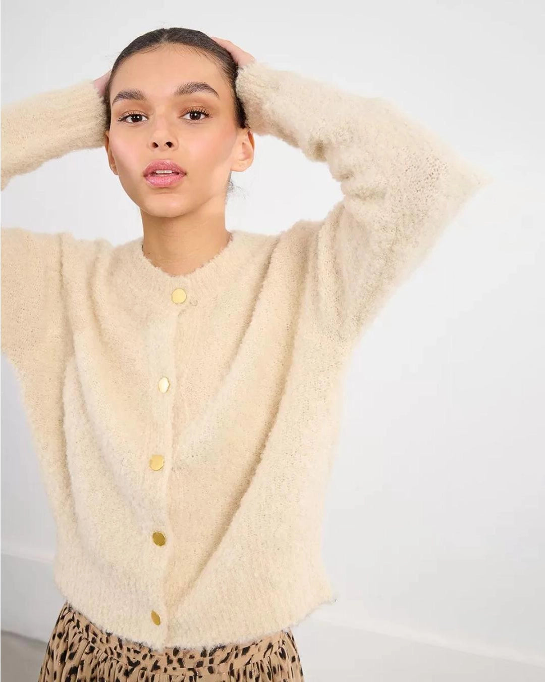 Woman wearing a beige fluffy cardigan with gold buttons