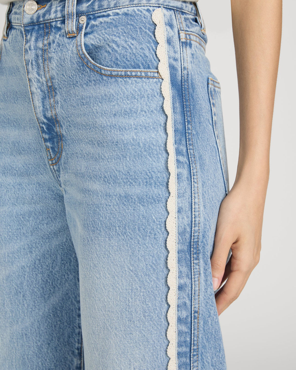 cropped light wash denim pant with a cream crochet detail on the sides