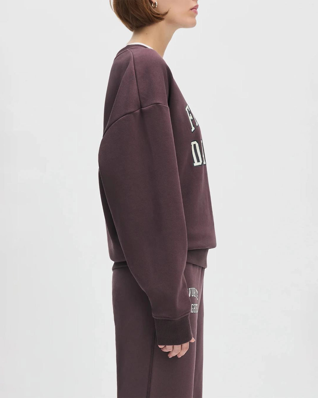 Woman wearing a maroon 'FAVORITE DAUGHTER' sweatshirt and matching sweatpants