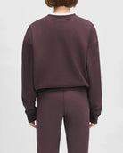 Woman wearing a maroon 'FAVORITE DAUGHTER' sweatshirt and matching sweatpants