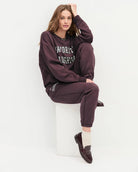 Woman wearing a maroon 'FAVORITE DAUGHTER' sweatshirt and matching sweatpants