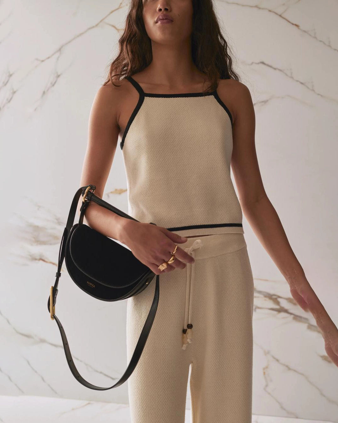 woman holding black suede shoulder purse on crook of her elbow with short and long strap