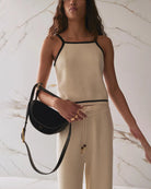 woman holding black suede shoulder purse on crook of her elbow with short and long strap