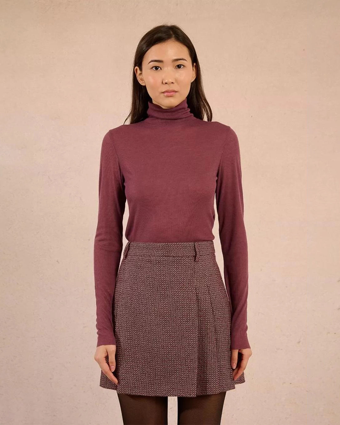 Woman wearing a rust coloured turtleneck sweater