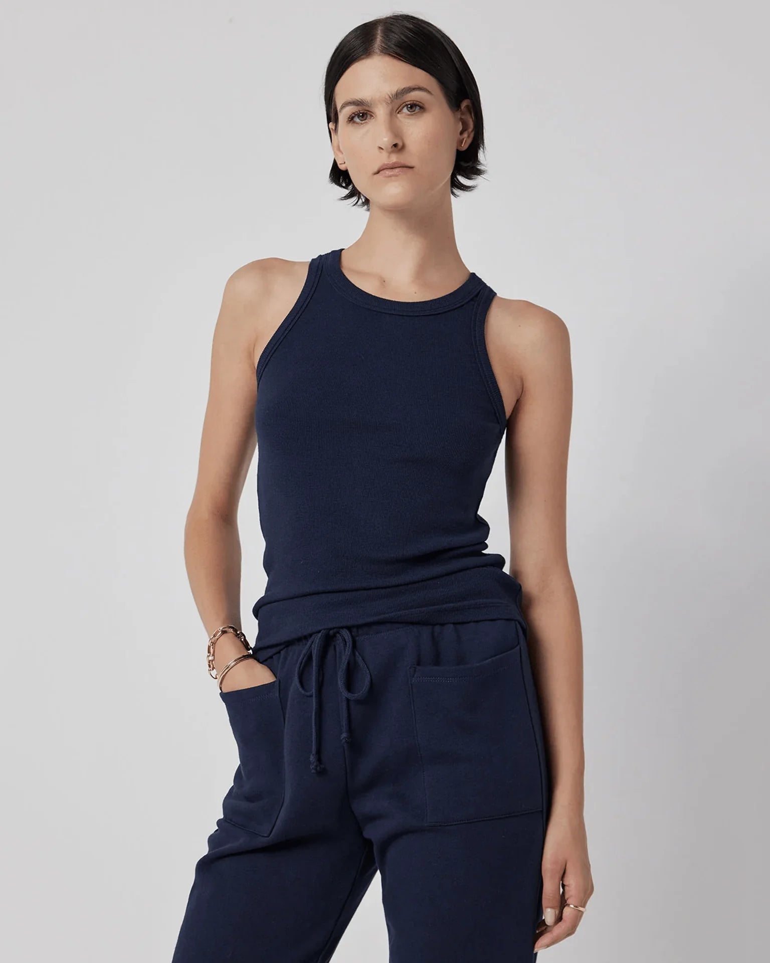 A woman wearing a navy blue ribbed tank top and grey trousers
