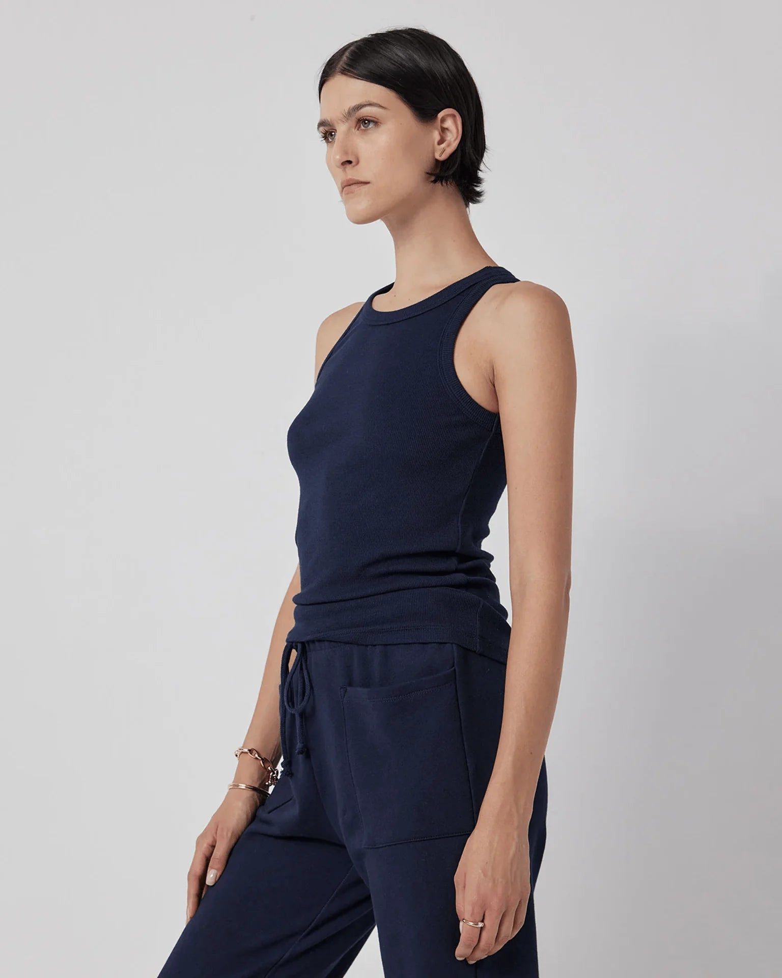 A woman wearing a navy blue ribbed tank top and grey trousers