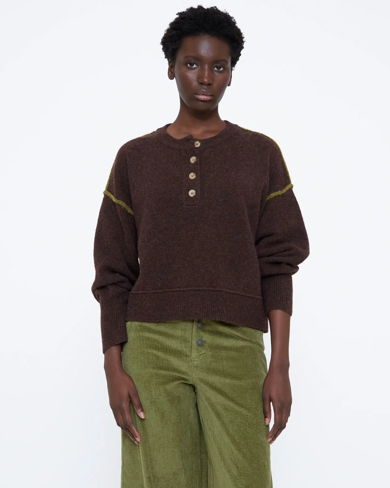 brown knit sweater with buttons half down and a green detail on sleeve