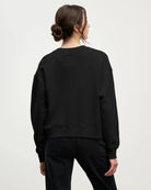 a woman wearing a cotton crew neck sweater in black