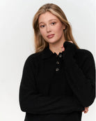 a woman wears a black ribbed knit polo sweater