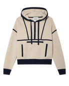 A woman wearing an ivory cashmere hoodie with navy accents