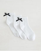 three pack crew socks in white with black bows on the back