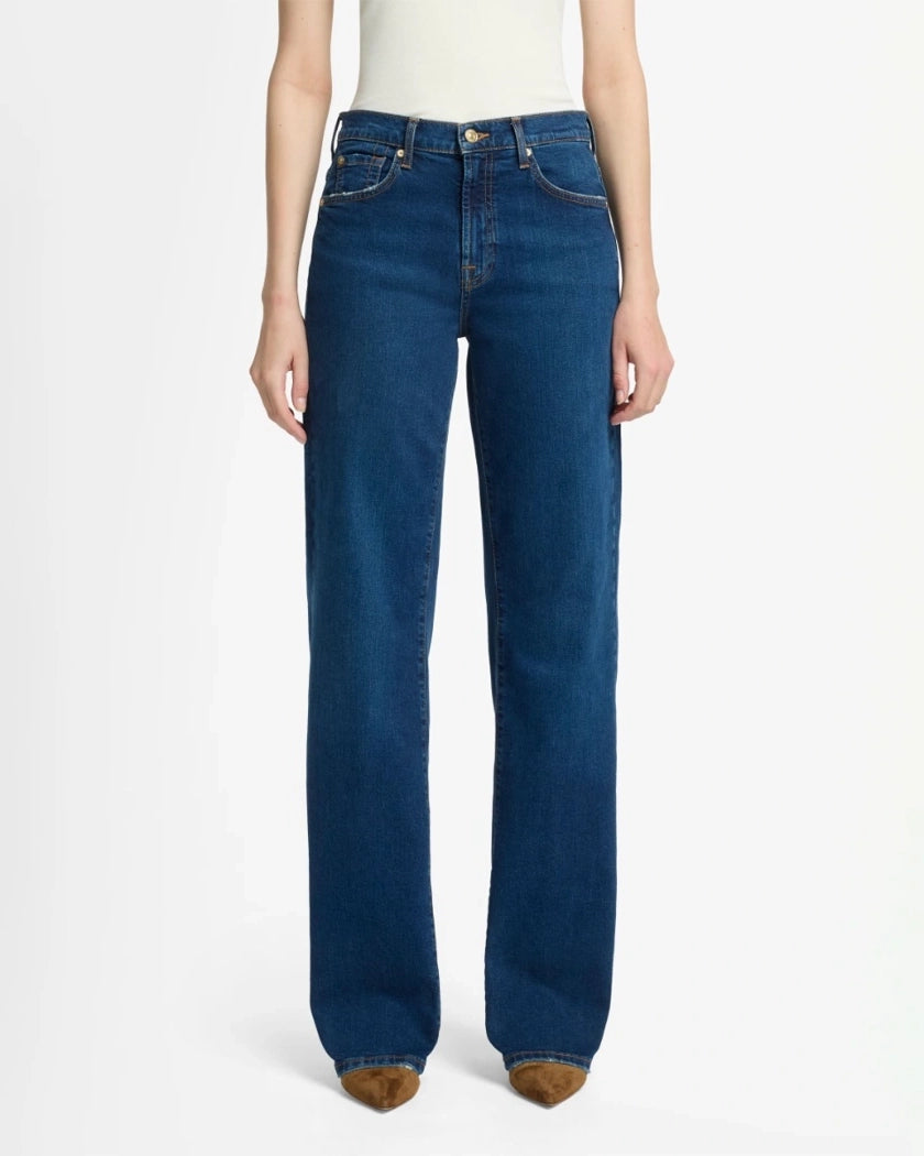 A woman wearing blue mid rise jeans by 7 For All Mankind