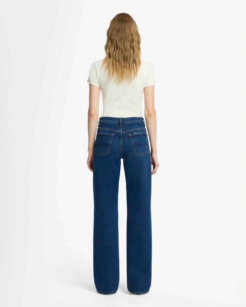 A woman wearing blue mid rise jeans by 7 For All Mankind