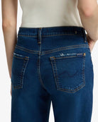A woman wearing blue mid rise jeans by 7 For All Mankind