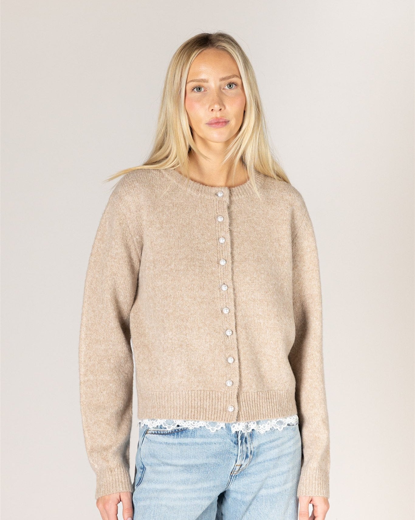 beige knit cardigan with pearl buttons and lace trim on the bottom