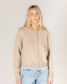 beige knit cardigan with pearl buttons and lace trim on the bottom