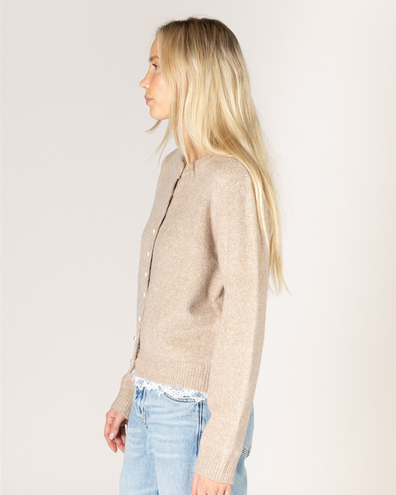 beige knit cardigan with pearl buttons and lace trim on the bottom