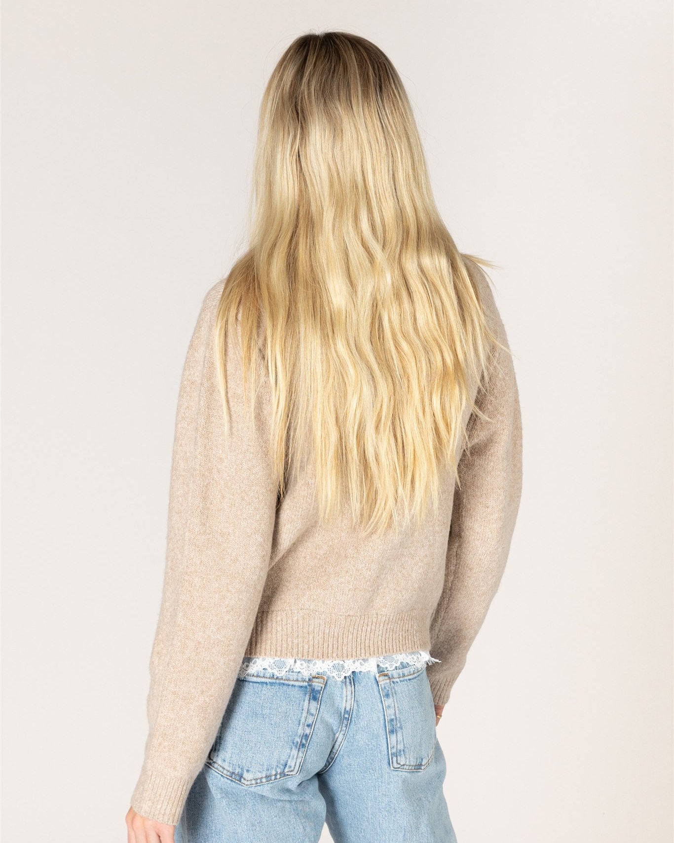 beige knit cardigan with pearl buttons and lace trim on the bottom