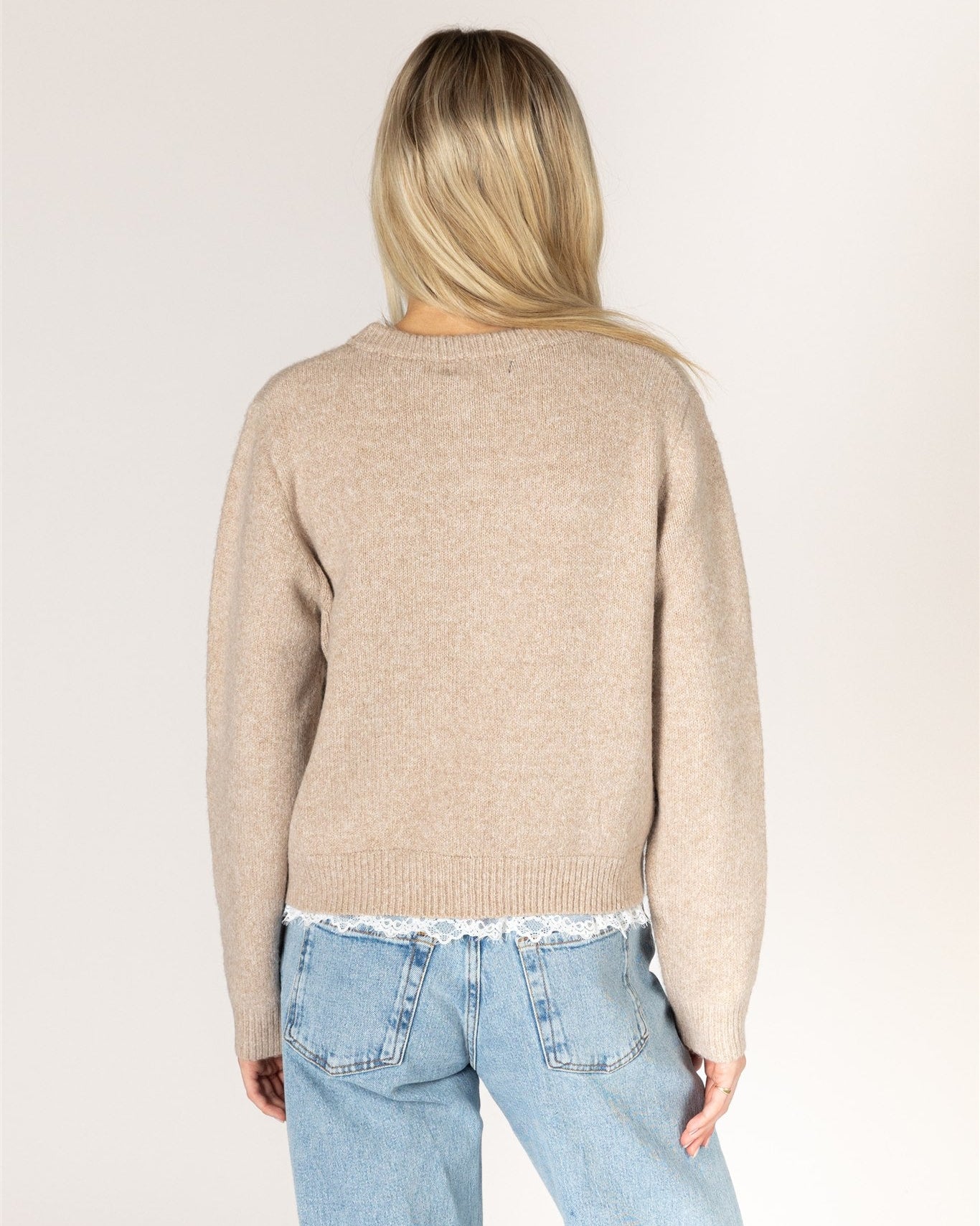beige knit cardigan with pearl buttons and lace trim on the bottom