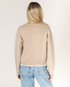 beige knit cardigan with pearl buttons and lace trim on the bottom