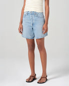 Person wearing mid rise light blue denim shorts 
