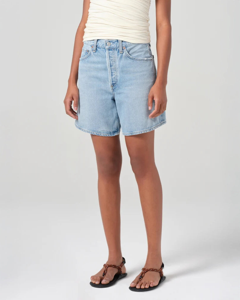 Person wearing mid rise light blue denim shorts 