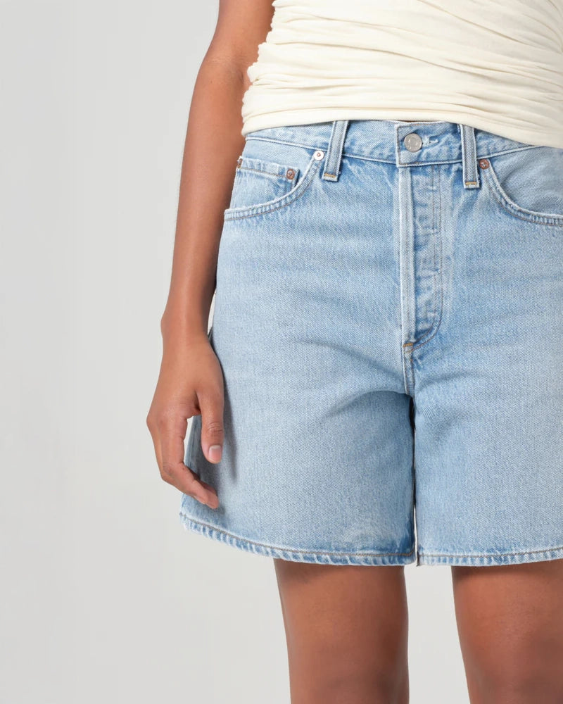 Person wearing mid rise light blue denim shorts 