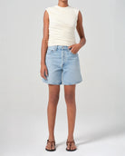 Person wearing mid rise light blue denim shorts 