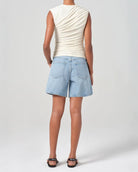 Person wearing mid rise light blue denim shorts 